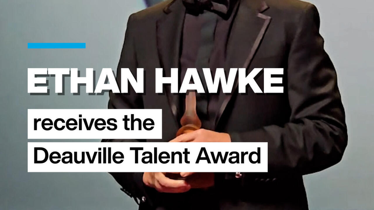 Man in dark suit holding a trophy, with overlaid text announcing a talent award.
