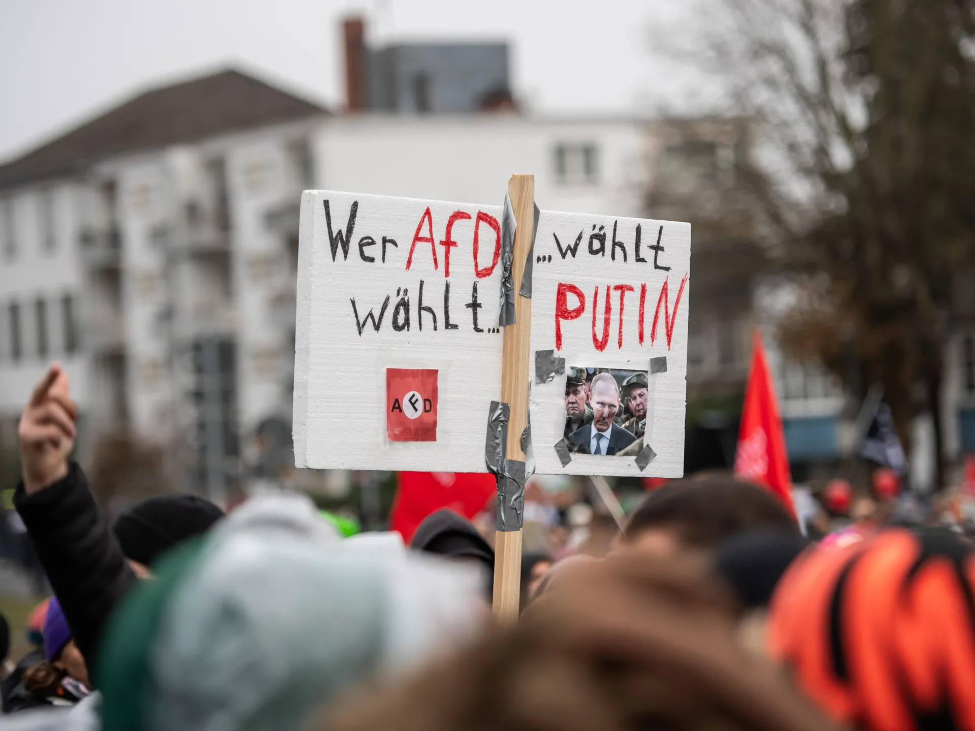 Protest sign reading “Wer AfD wählt … wählt Putin” held above a blurred crowd.