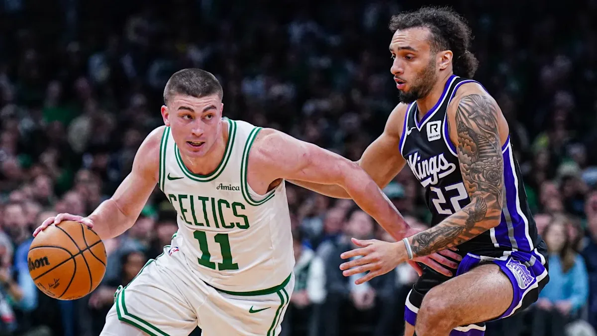 Celtics player dribbles past a Kings defender during a basketball game