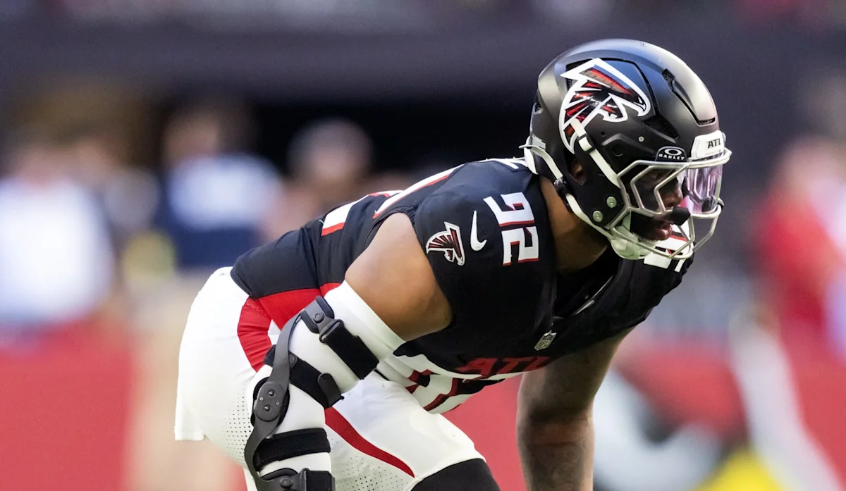 Atlanta Falcons football player in black uniform and helmet crouches before a play.