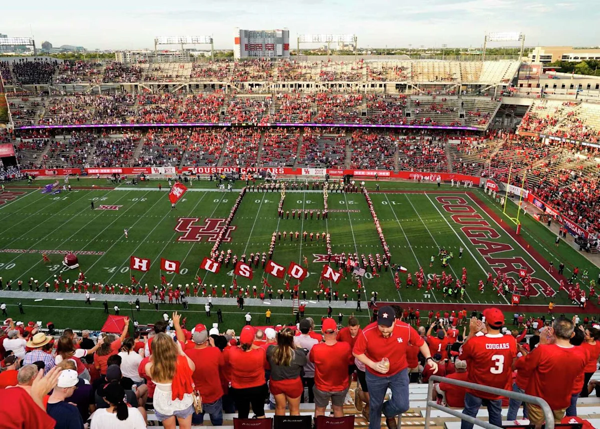 Crowded football stadium with fans surrounding players and performers arranged on the field.