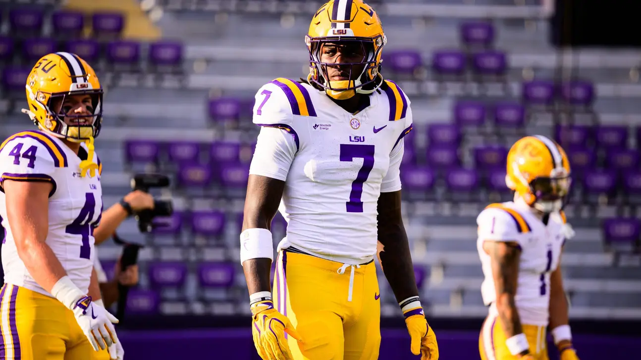 LSU football players in purple and gold uniforms standing on a field before a game
