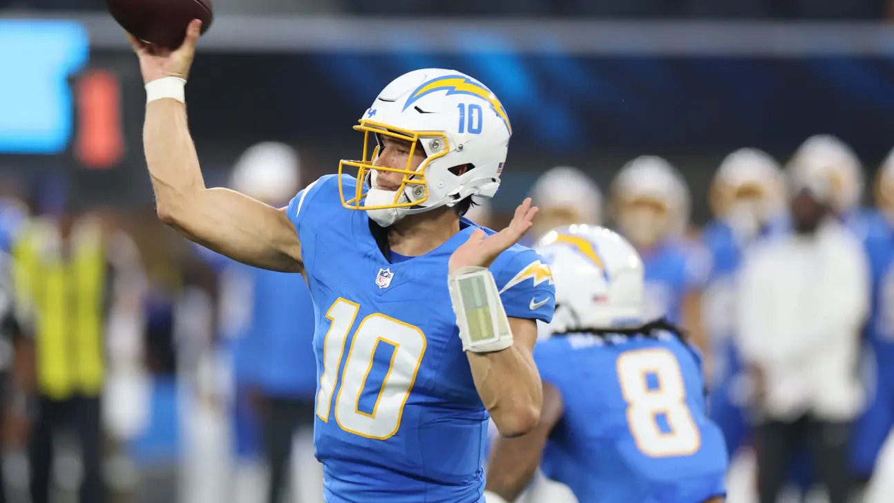 Football quarterback in blue Chargers uniform throws a pass during an NFL game.
