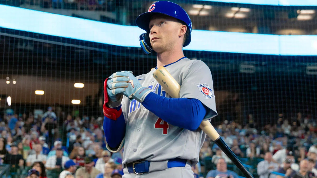 Baseball player in gray uniform and blue helmet holding a bat during batting practice