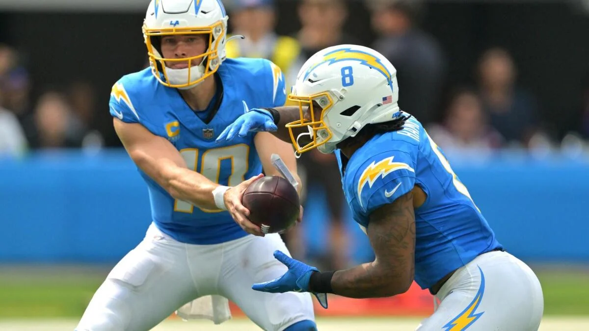 Two Los Angeles Chargers players in blue uniforms execute a handoff during a football game