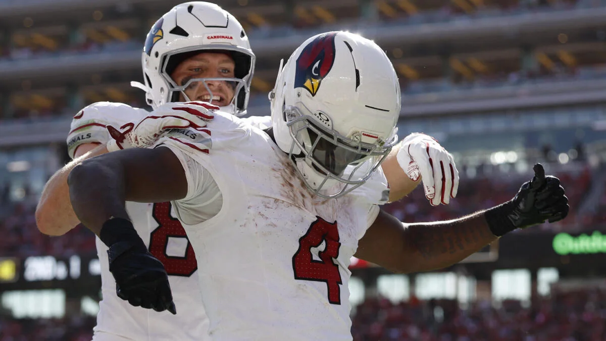 Two Arizona Cardinals players in white uniforms celebrate together on the field during a game.