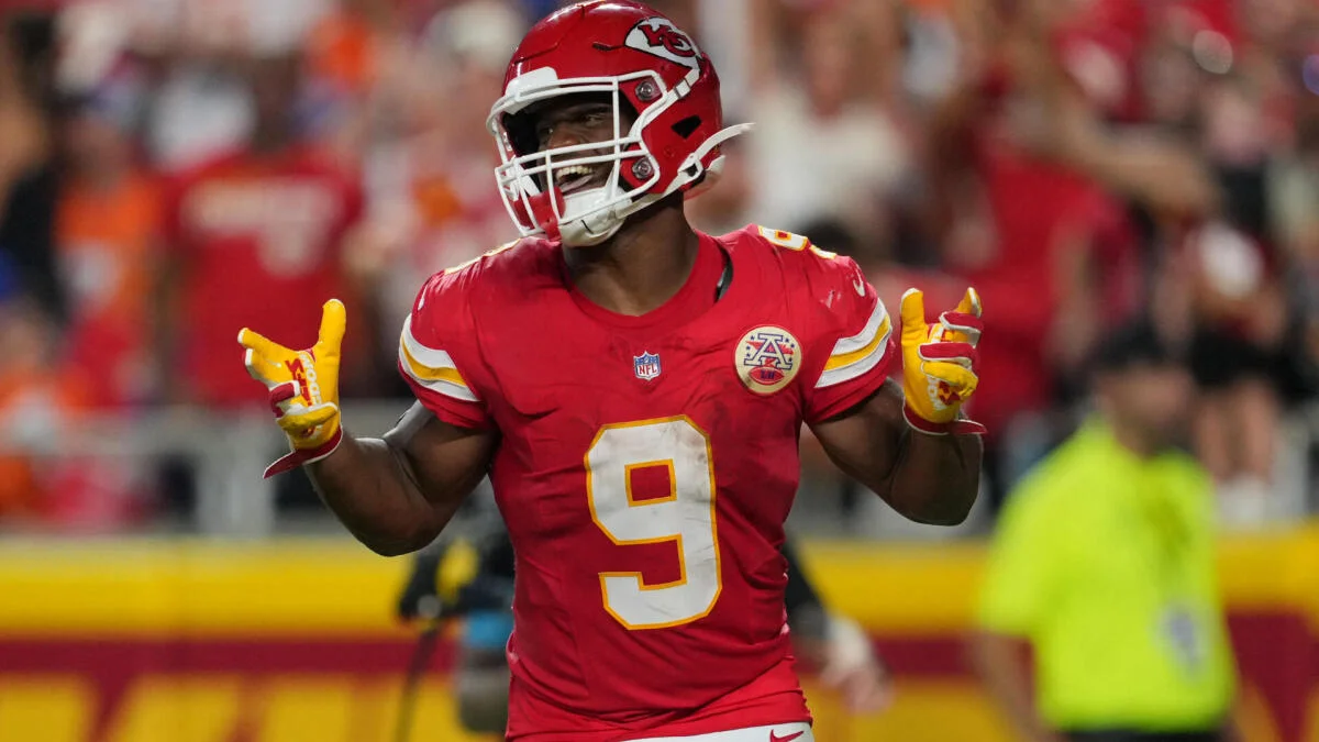 Kansas City Chiefs running back in red uniform gestures with both hands during a game