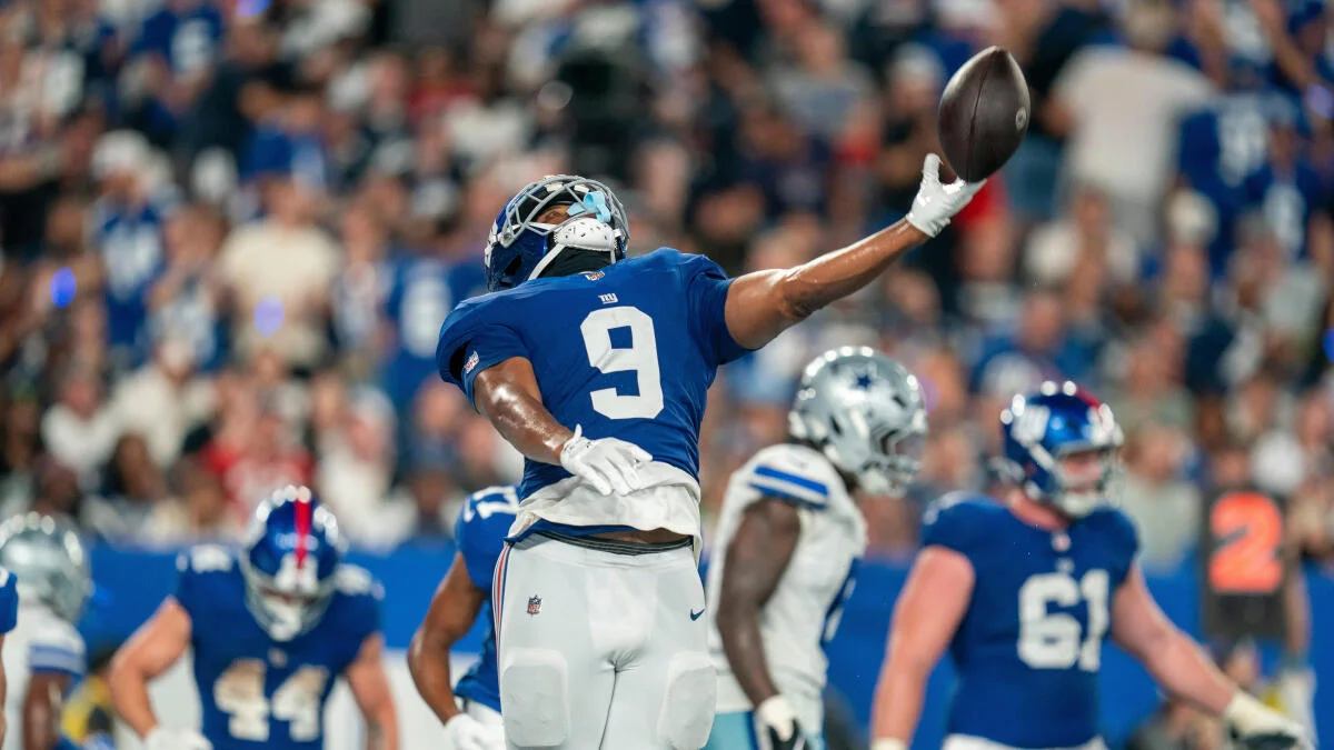 Football player in blue jersey reaches one-handed for a ball during a game