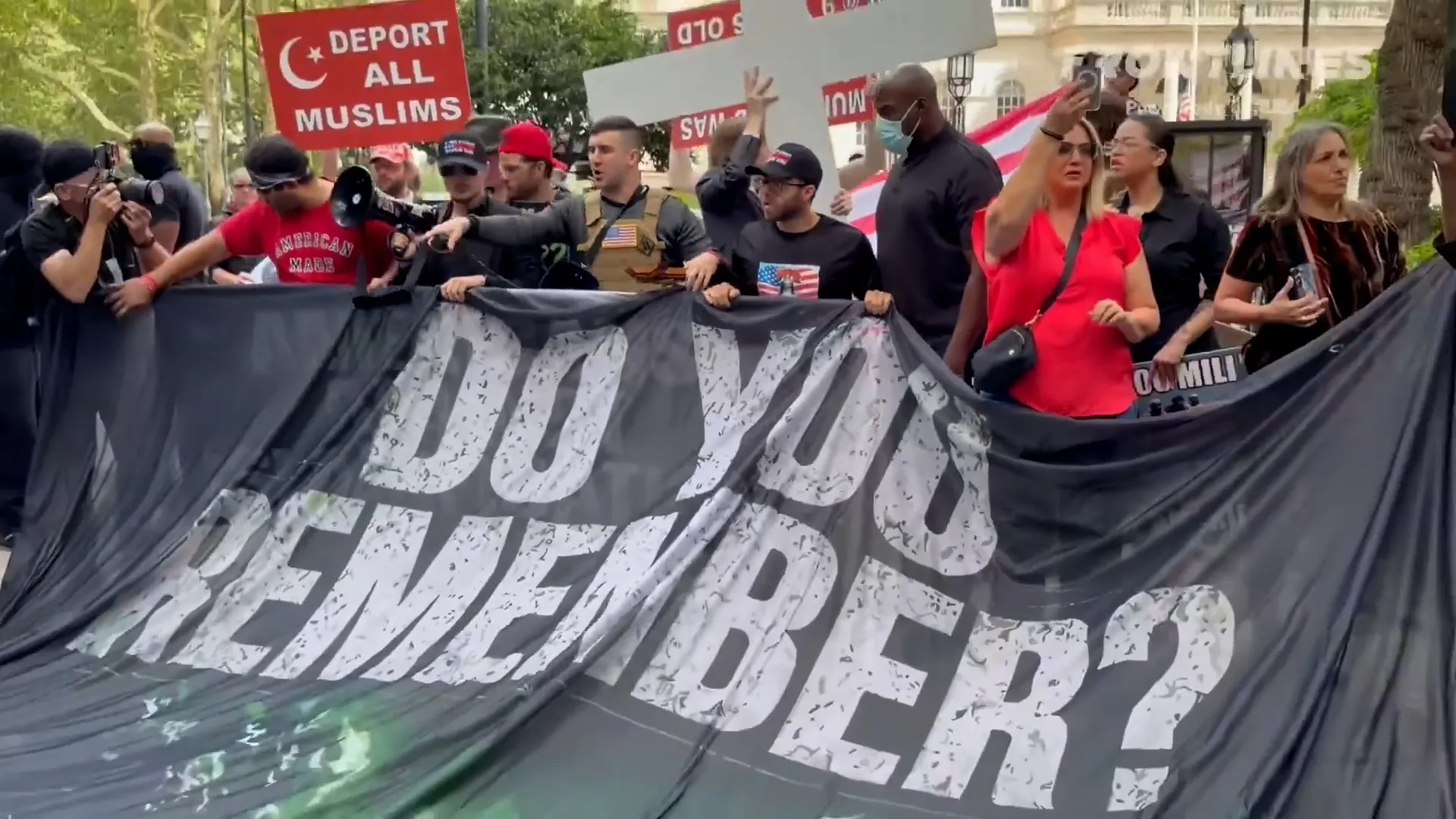 Protesters hold a large banner and signs, including one reading “Deport All Muslims.”