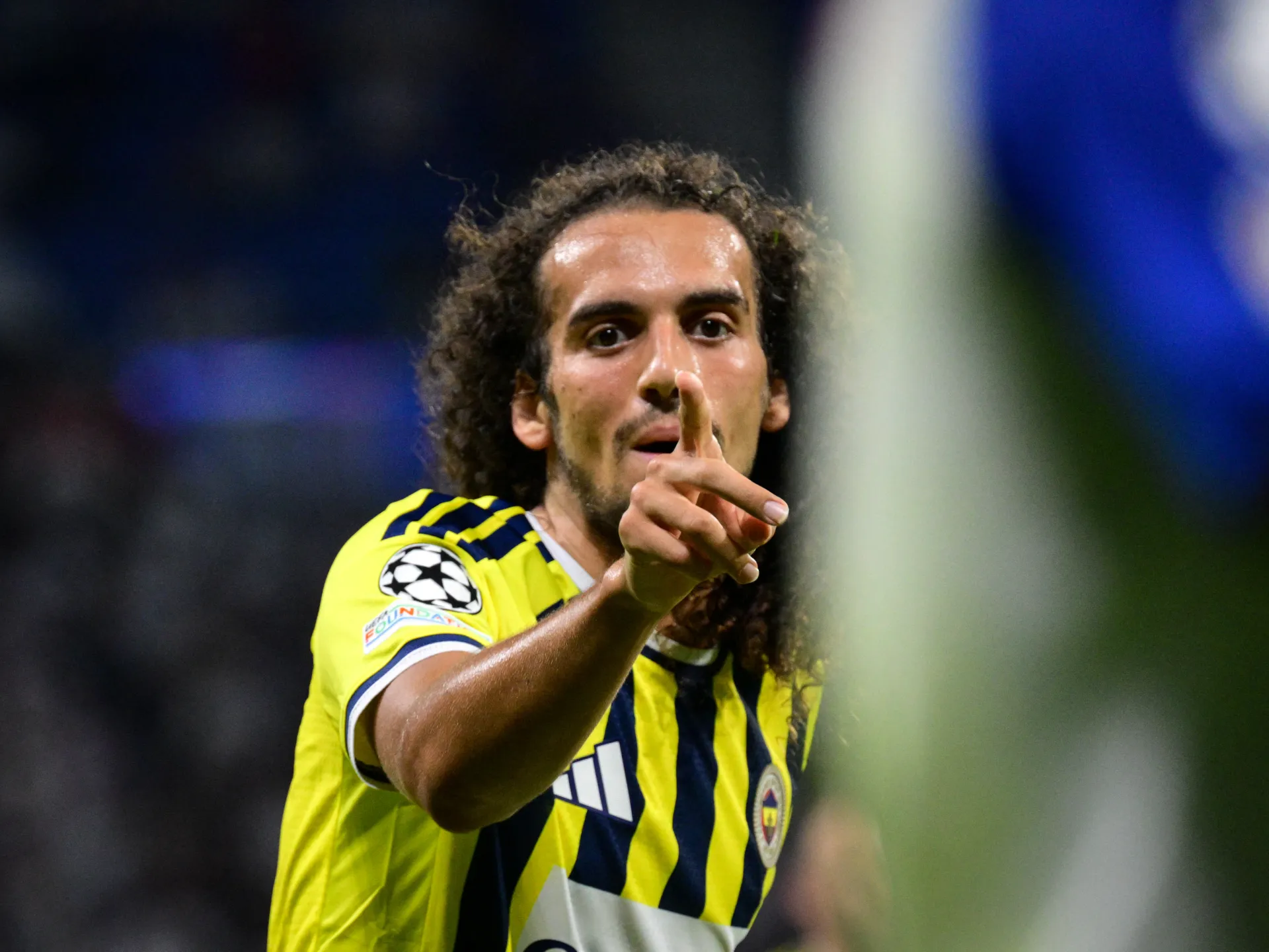 Fenerbahce footballer in yellow and navy jersey holding a finger to his lips