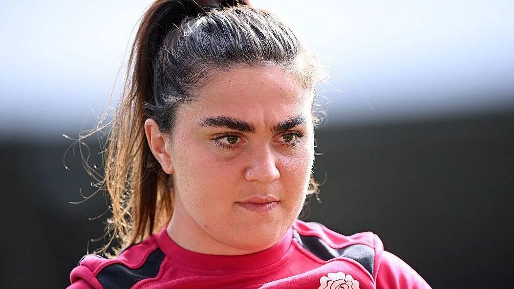 Close-up of a female rugby player in a red jersey looking ahead during a match.