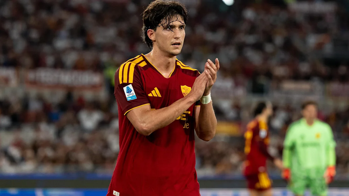 A Roma player in a red jersey claps on the pitch during a match.