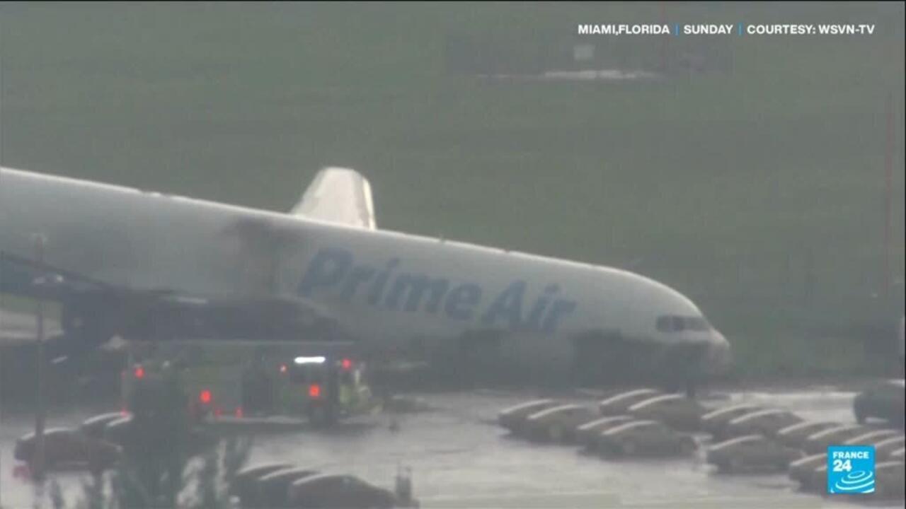 Prime Air cargo plane sits on a rain-soaked airport tarmac as emergency vehicles approach.