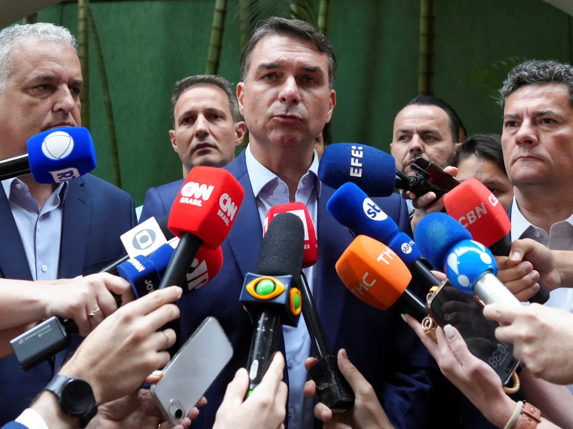 Brazilian politician surrounded by reporters and microphones during a press briefing