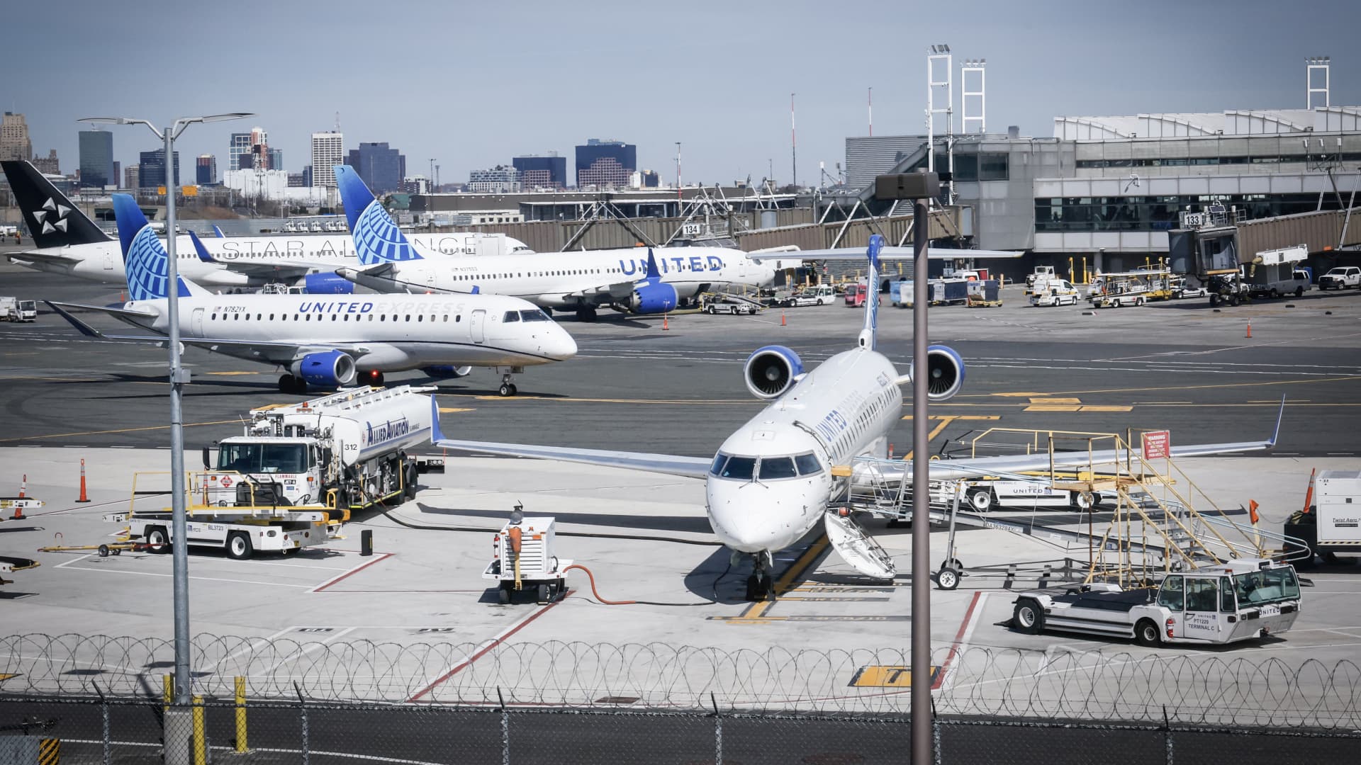 Several United Airlines aircraft parked at airport gates with ground vehicles and terminal buildings visible