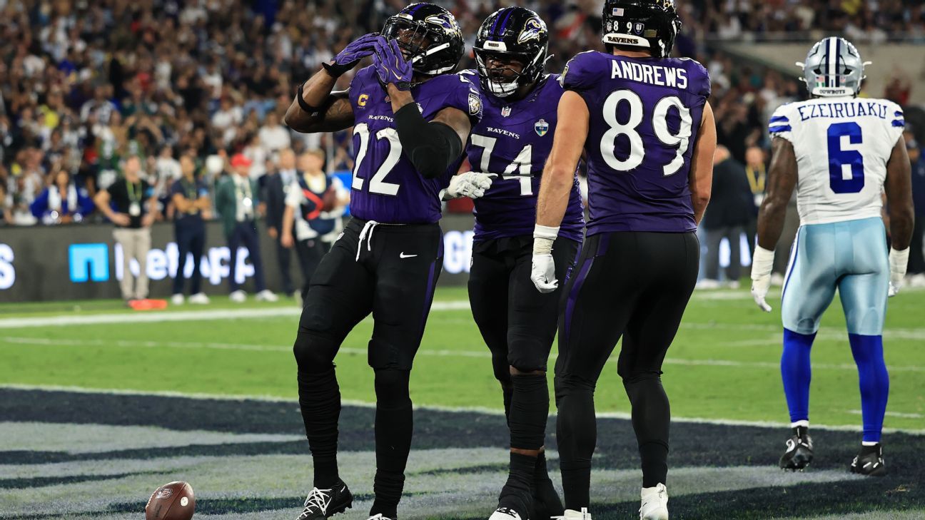 Three Ravens players celebrate on the field as a Cowboys player walks away nearby.
