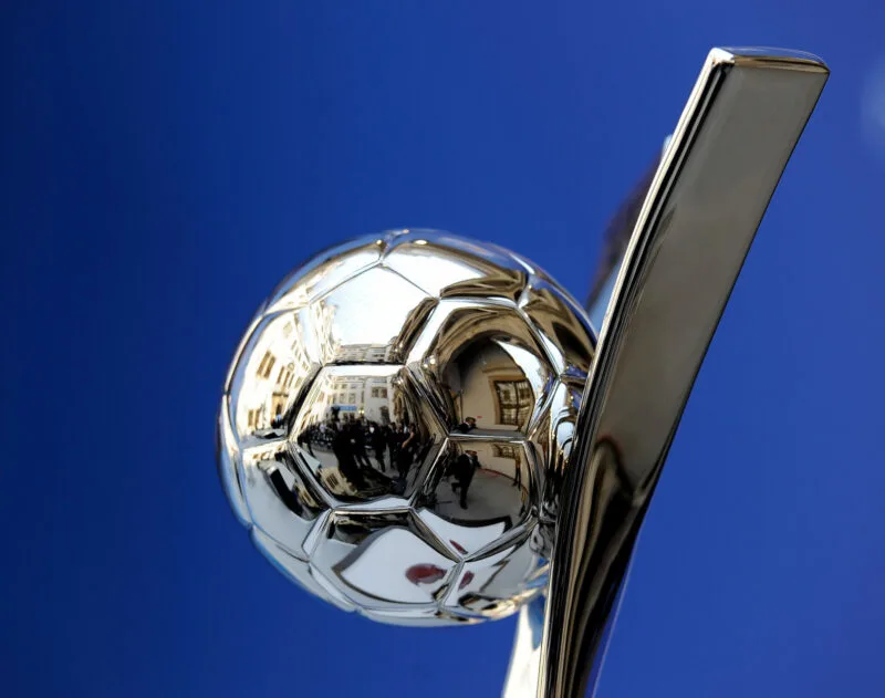 Reflective silver football trophy against a deep blue background