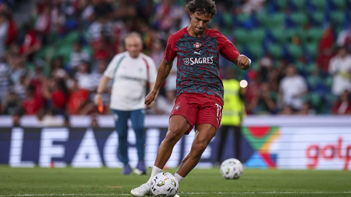A Portugal player in a red kit strikes a ball during a match as spectators watch.