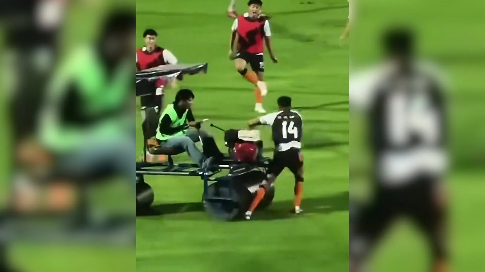 Football players gather around a person seated on a small pitch vehicle during a match
