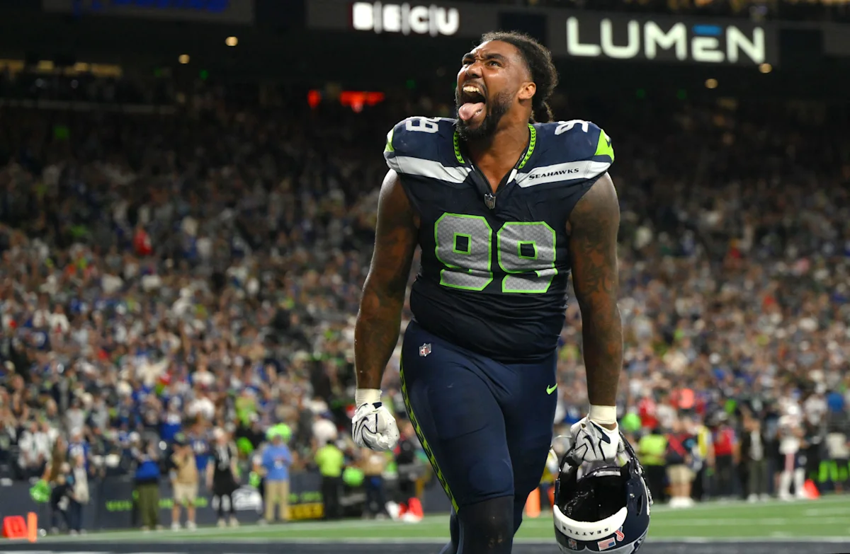 Seattle Seahawks player wearing number 99 celebrates while carrying his helmet on the field