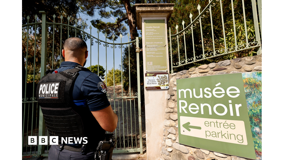 Municipal police officer stands outside a gated Renoir museum entrance beside directional signage.