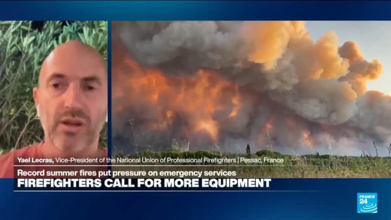 Television split-screen shows a firefighter speaking beside towering flames and thick wildfire smoke.
