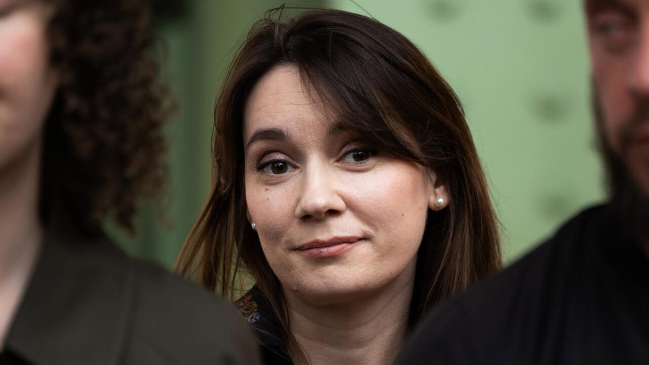 Woman looking toward the camera between two blurred people in the foreground
