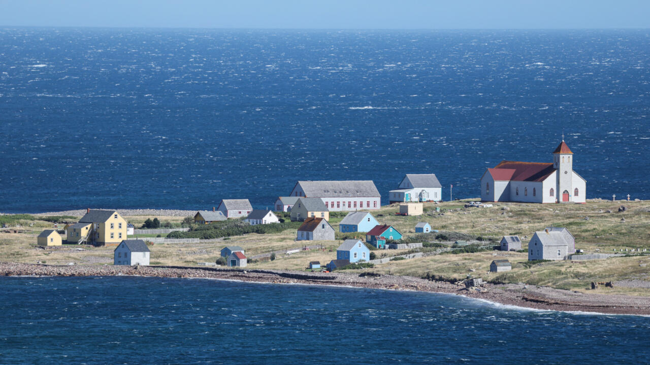 Coastal settlement with colorful houses and a white church beside the open ocean