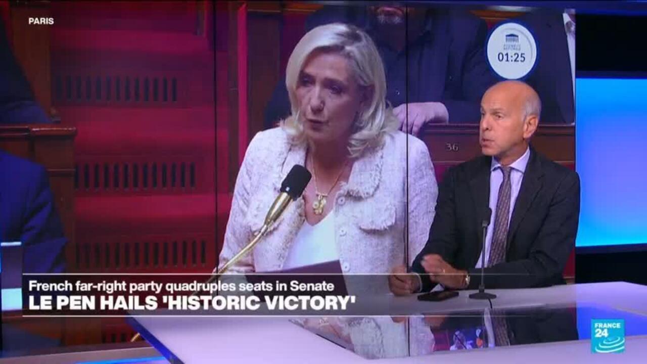 Marine Le Pen speaks on a studio screen as a male commentator sits at a desk beside it.