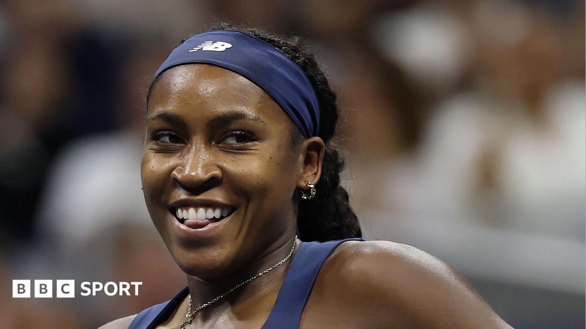 Smiling female tennis player wearing a navy headband and athletic top