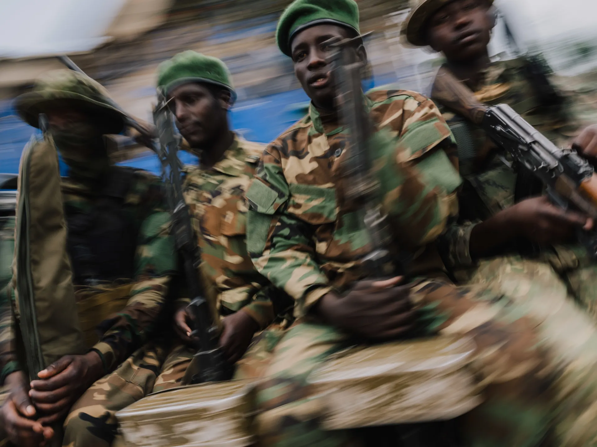 Soldiers in camouflage uniforms carry a covered stretcher amid heavy motion blur.