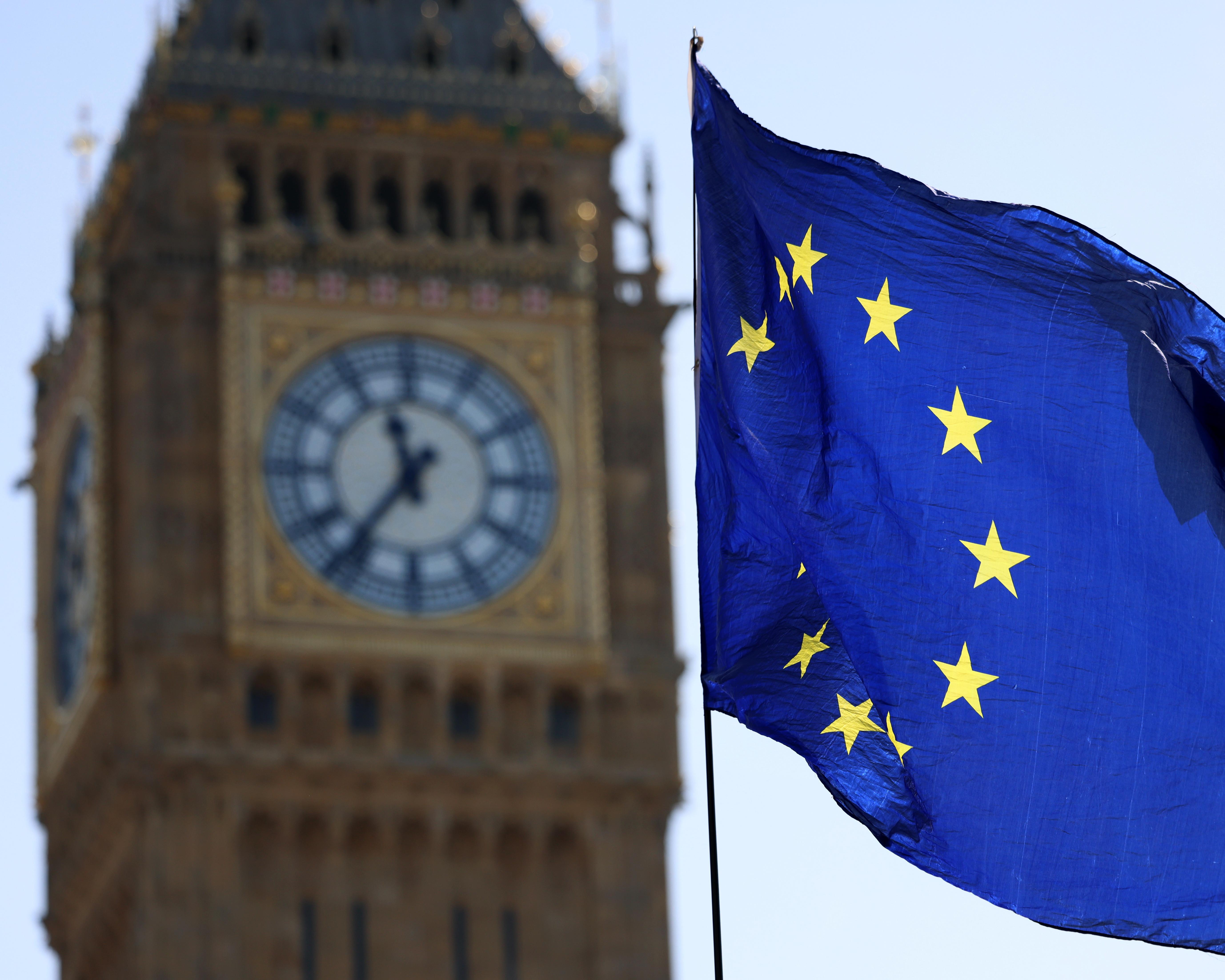 European Union flag waving in front of London’s blurred Elizabeth Tower clock face