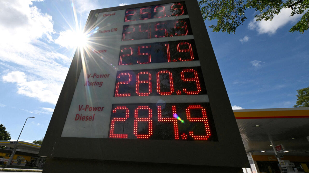 Fuel station price sign displaying petrol and diesel prices beneath a bright sunlit sky
