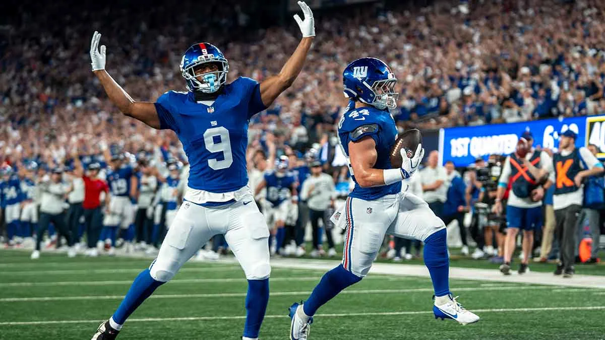 Two New York Giants players celebrate on the field during a football game.