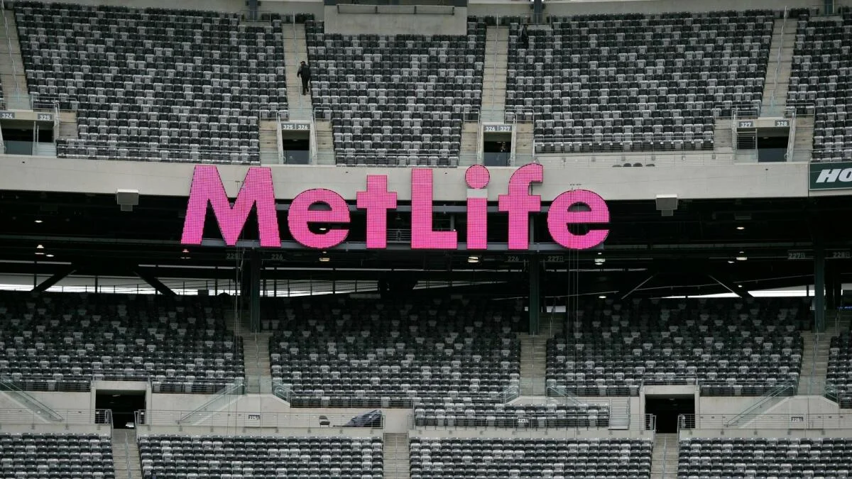 Large pink MetLife sign above rows of empty stadium seats.