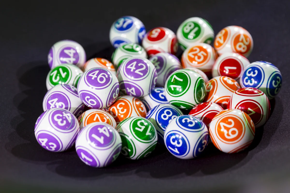 Colorful numbered lottery balls piled together on a dark surface
