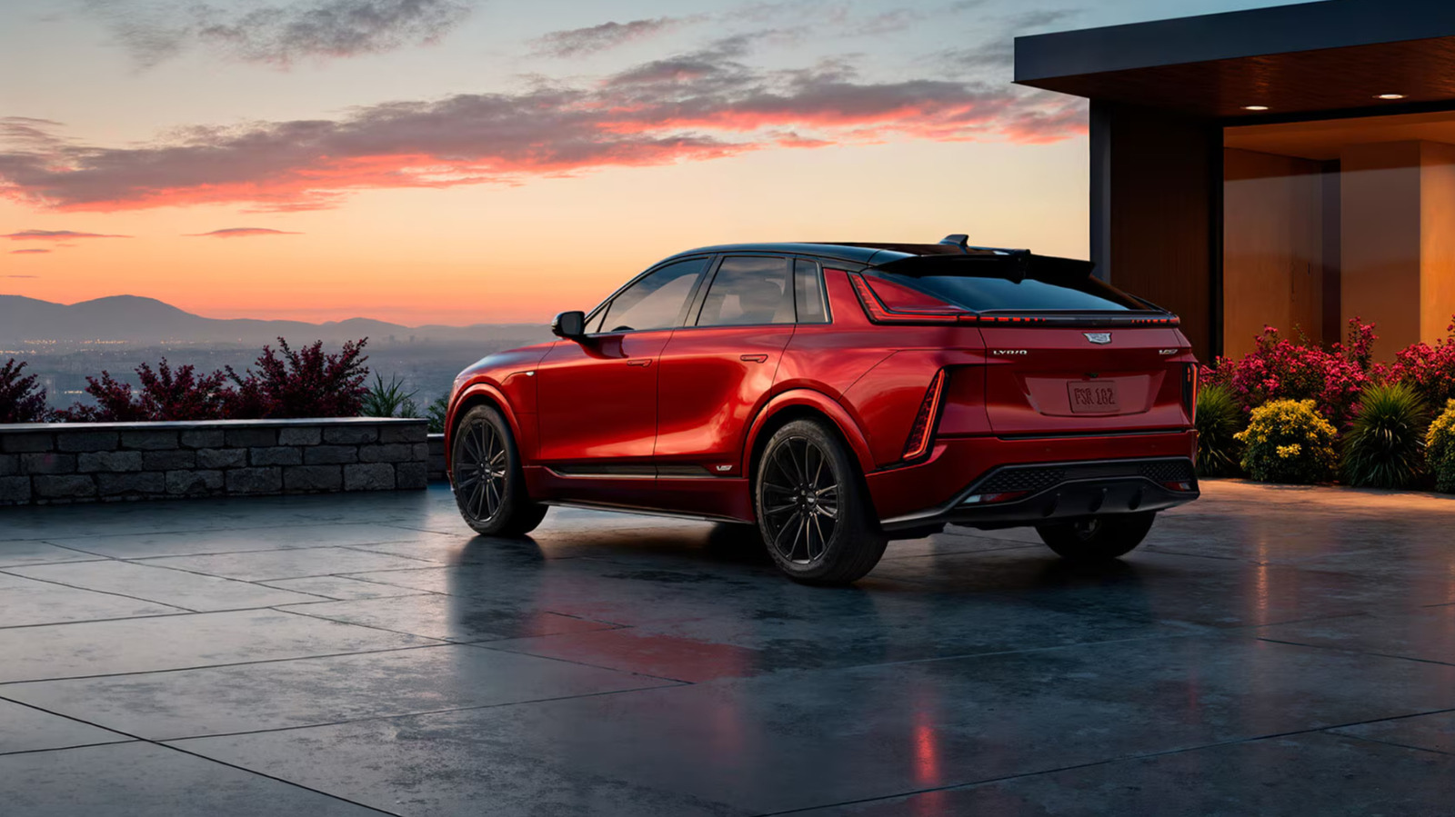 Red SUV parked on a modern home’s terrace at sunset, with mountains in the background.