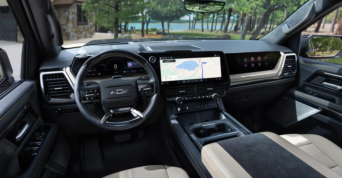Pickup truck interior with Chevrolet steering wheel, digital displays, navigation screen, and center console.