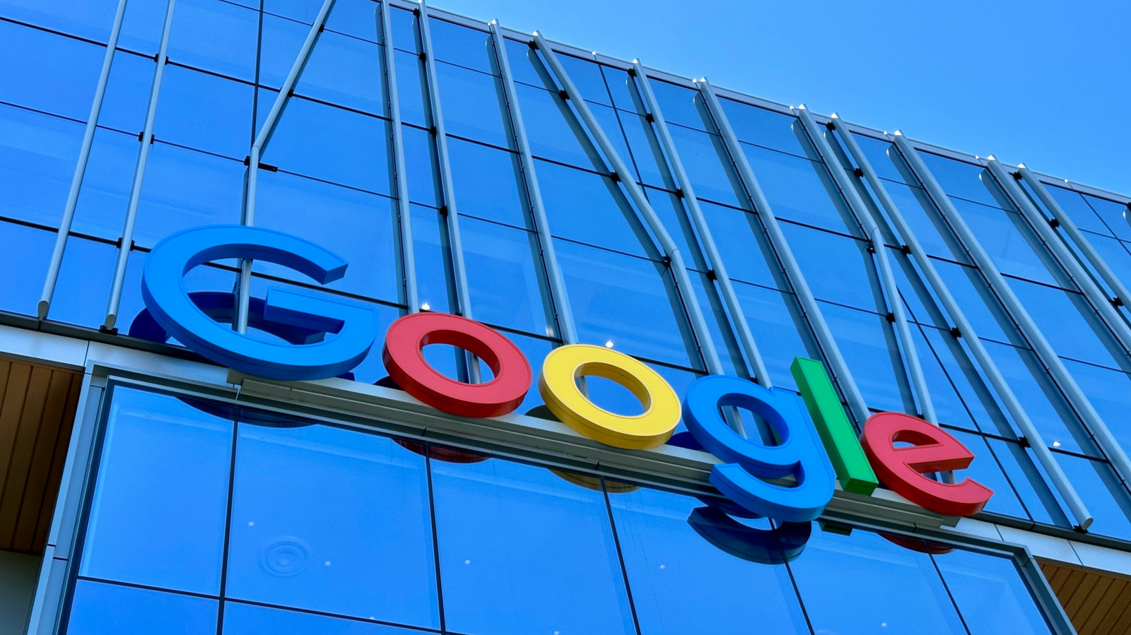 Colorful Google logo mounted on the glass facade of a modern building under a blue sky