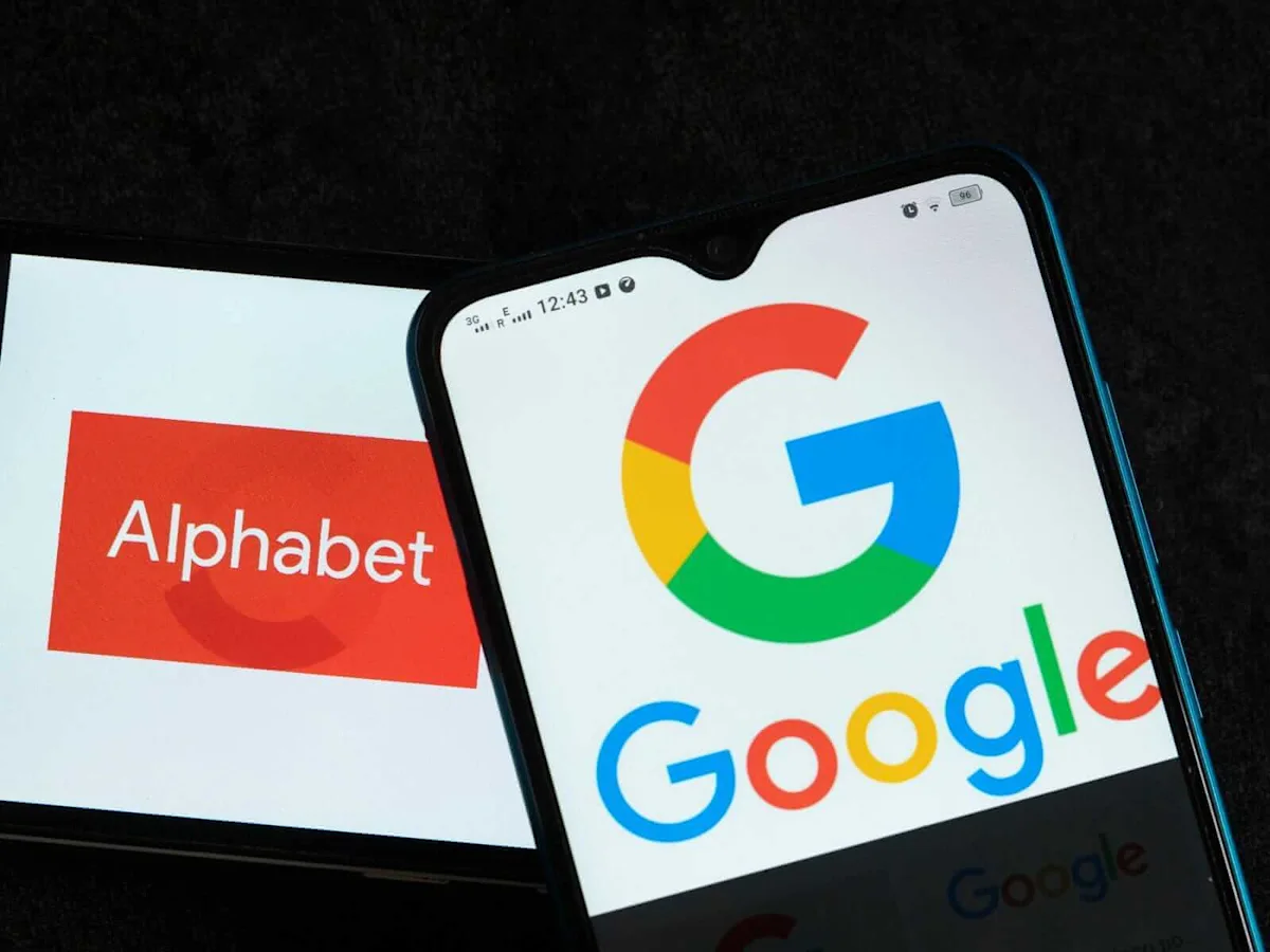 A smartphone displaying the Google logo rests over a screen labeled Alphabet.