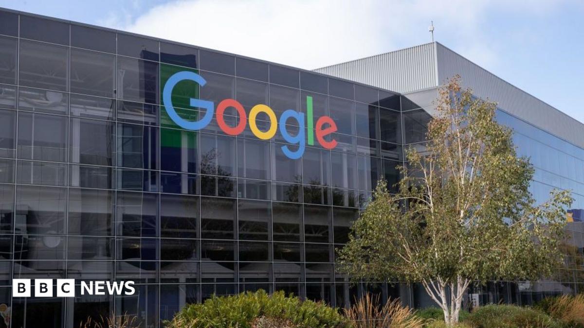 Google logo displayed on the glass facade of a modern office building beneath a partly cloudy sky