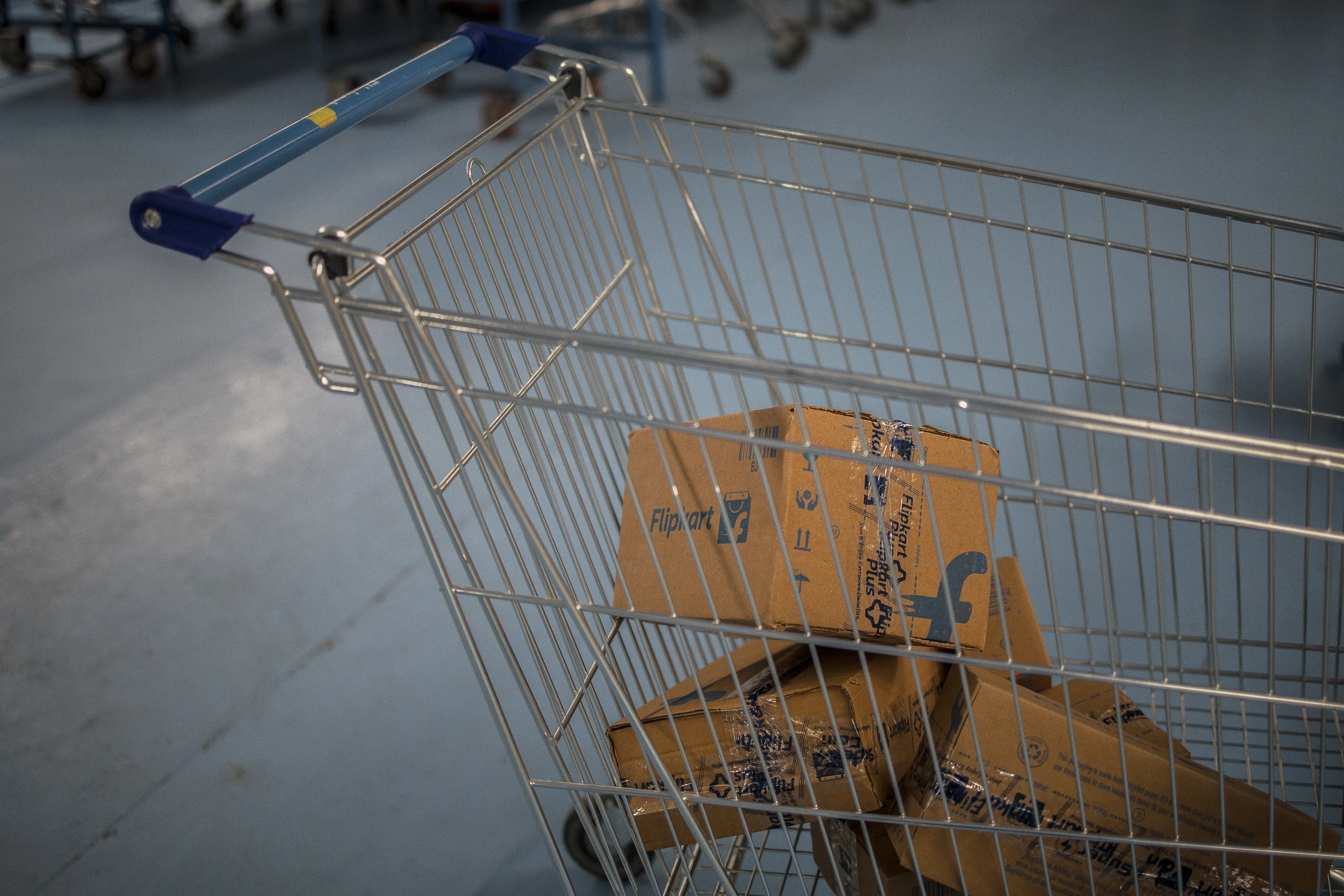 Cardboard Flipkart packages sit in a metal shopping cart with a blue handle.