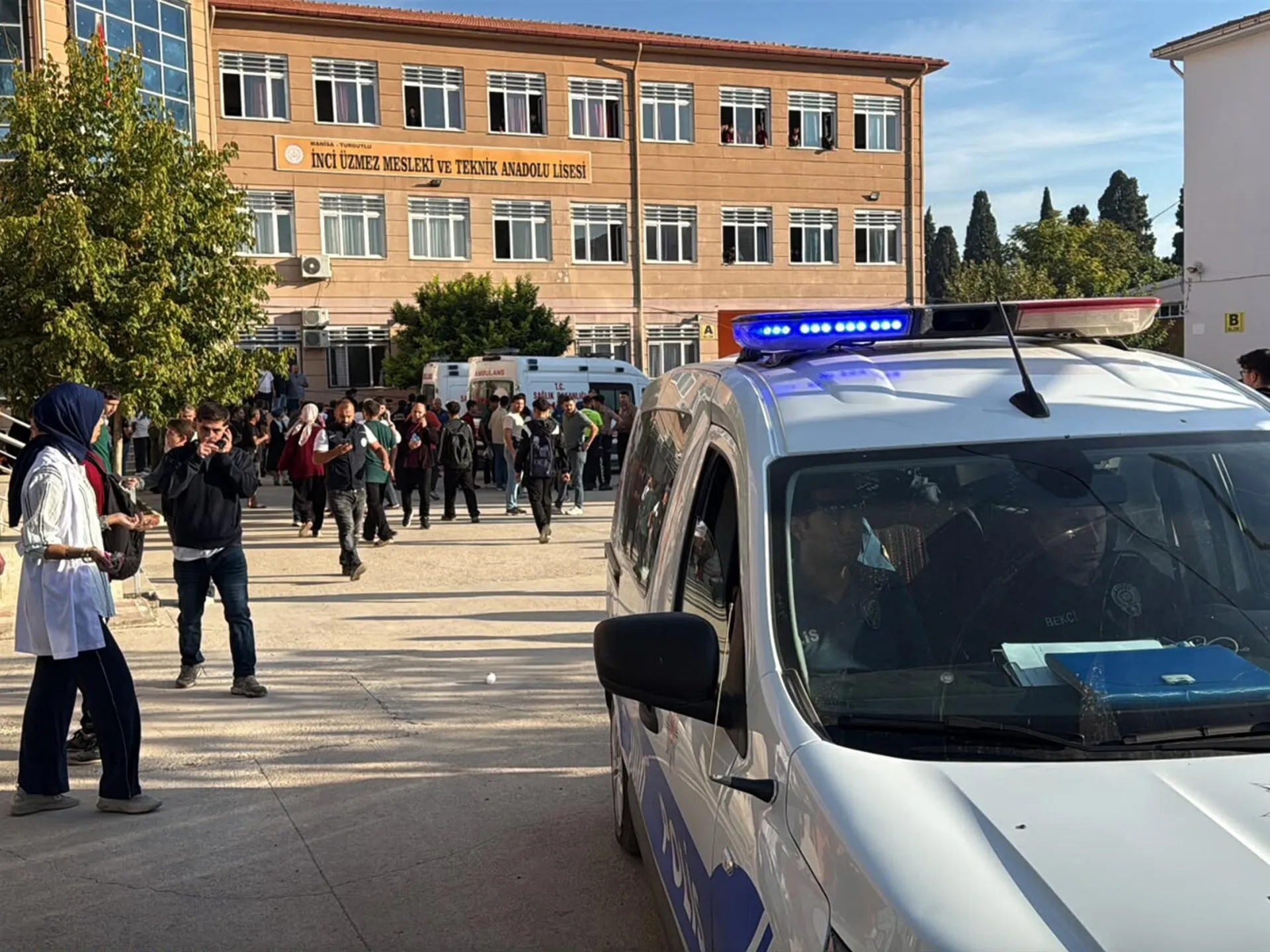 Ambulance and police vehicle outside a Turkish high school as students gather nearby