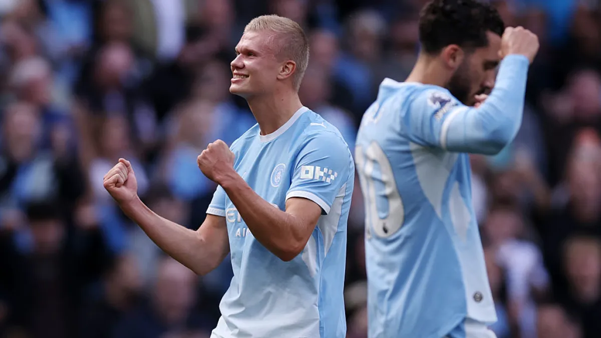 Manchester City players celebrate during a match, with one raising clenched fists.