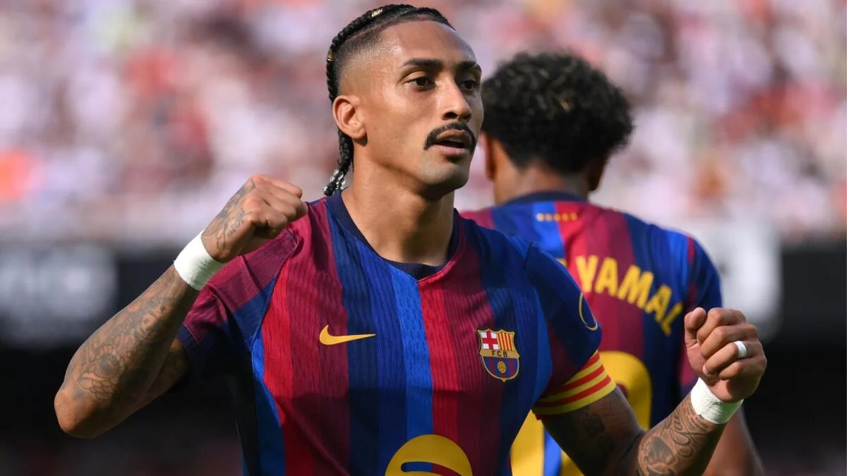 Barcelona footballer with braided hair raises a fist during a match, teammate visible behind him
