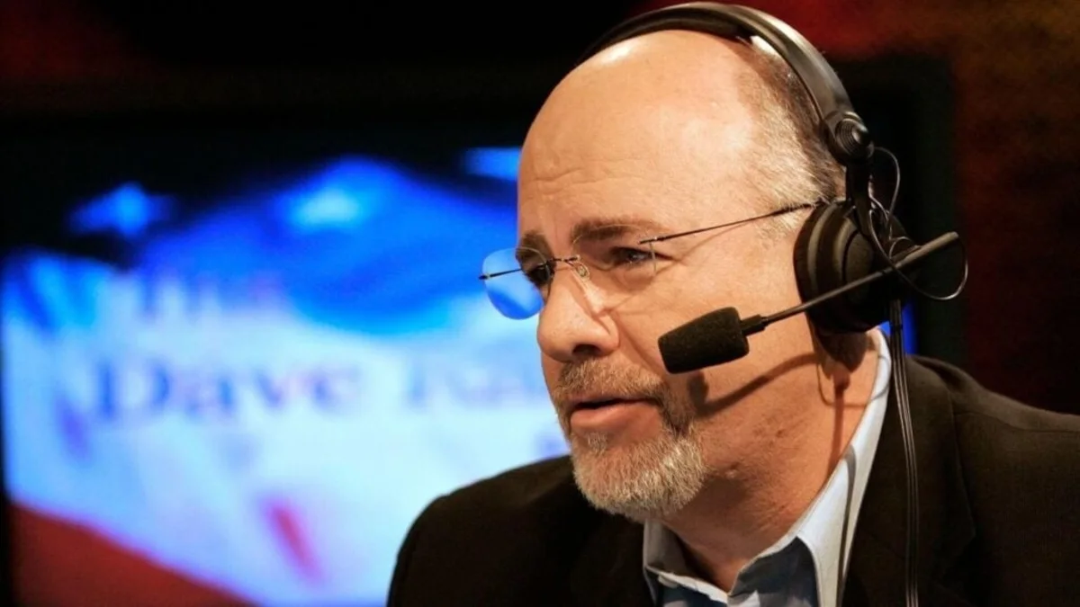 Bald man wearing glasses and a headset speaks during a broadcast.