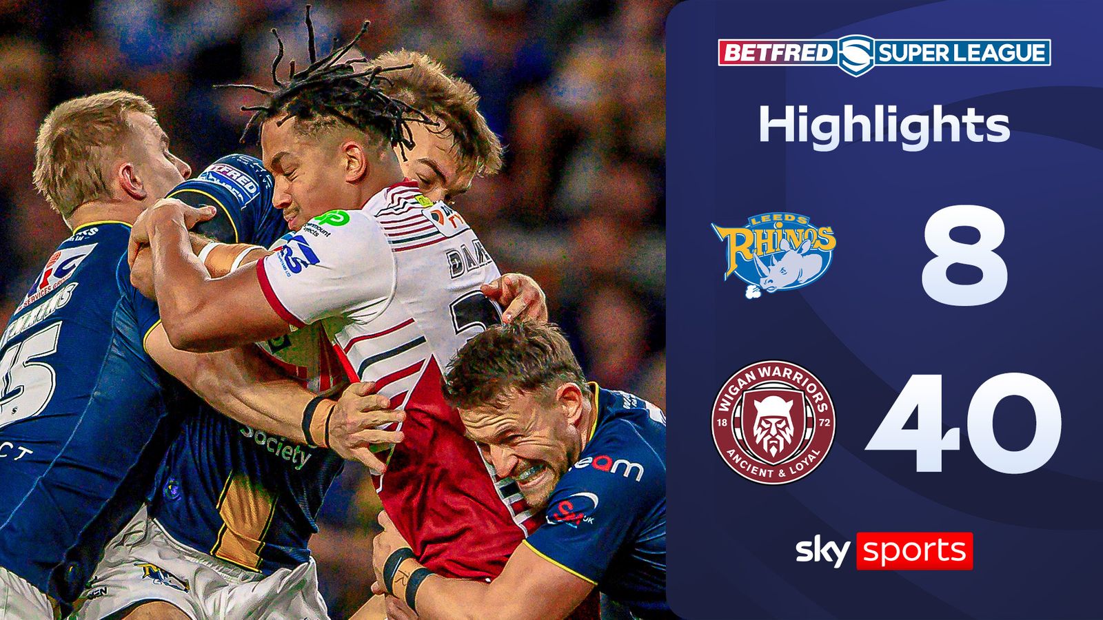 Rugby league players grapple during a match beside a scoreboard showing Leeds 8, Wigan 40