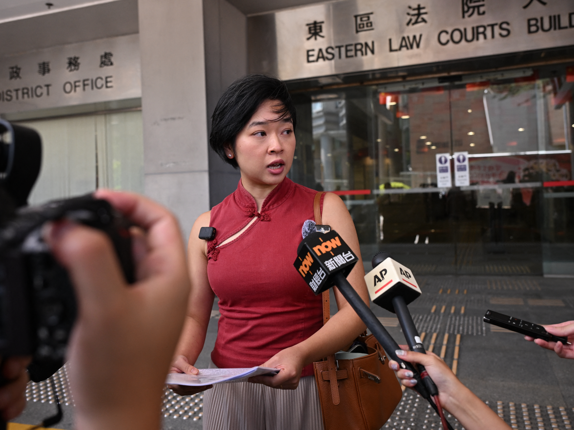 Woman speaking to reporters outside Eastern Law Courts Building as microphones are held toward her