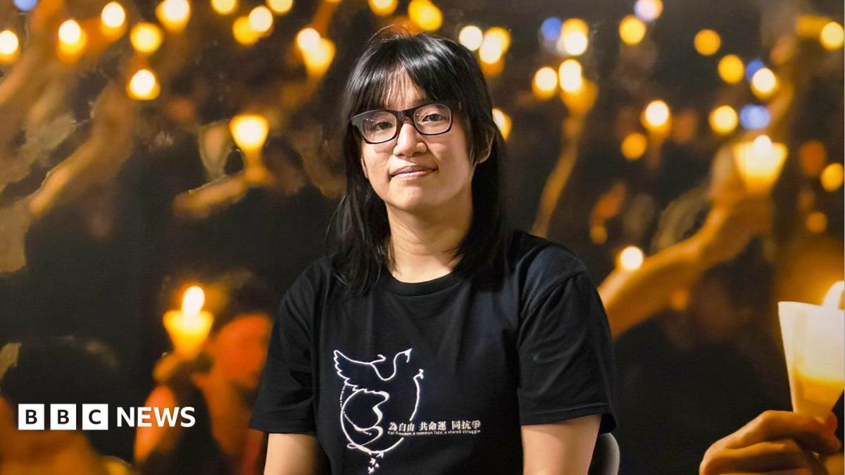 Woman wearing glasses and black T-shirt amid candlelit lights, with BBC News logo