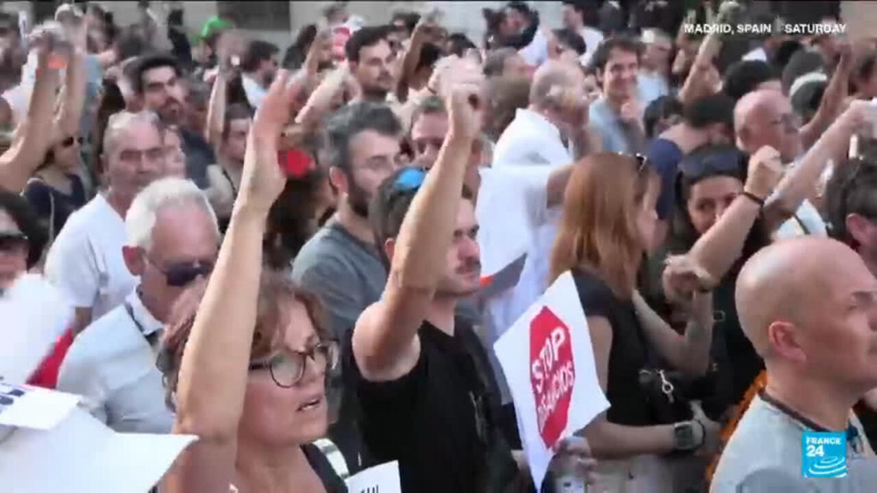 Crowd of protesters raises hands and holds signs, including one reading “Stop evictions.”